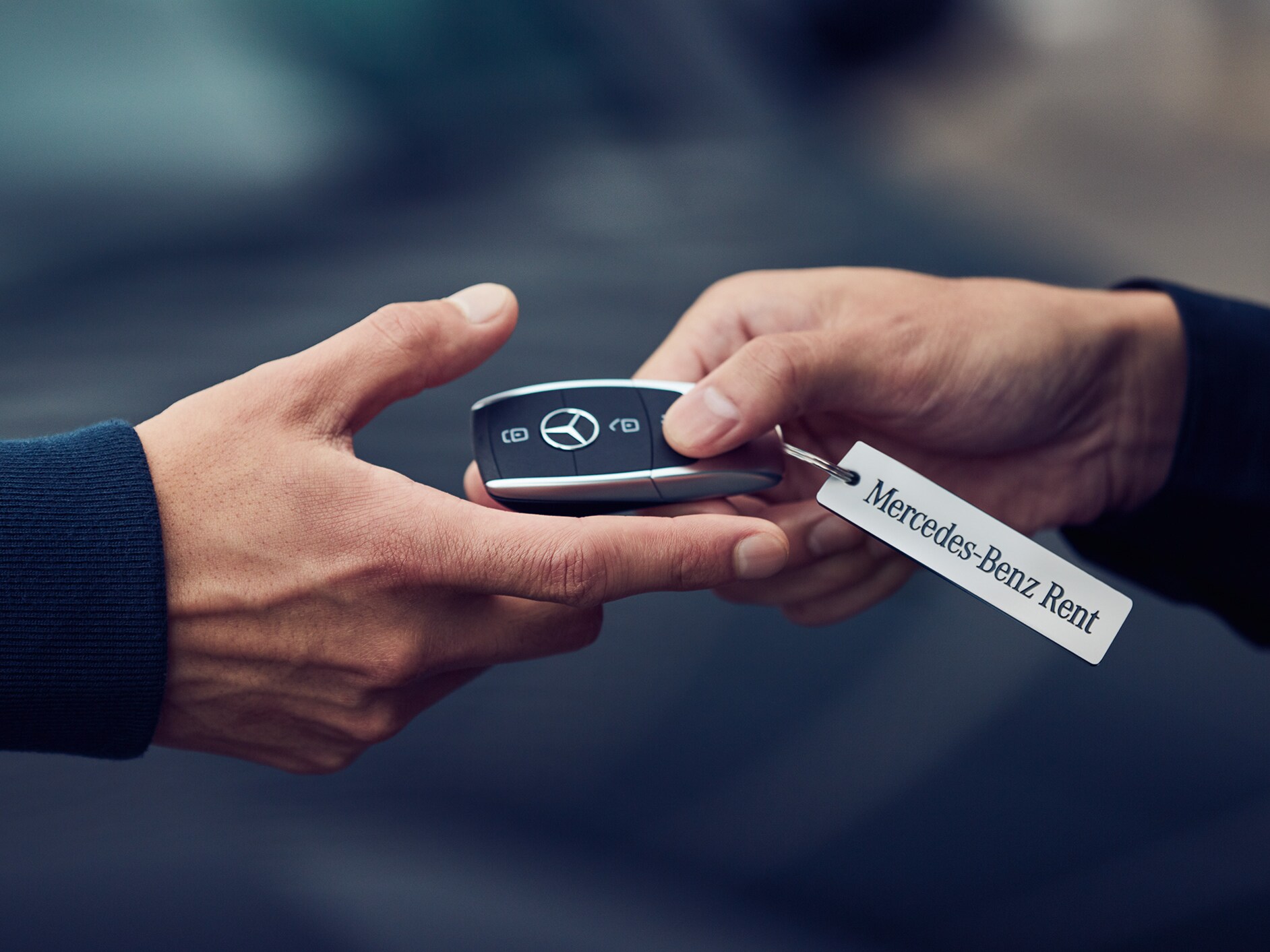 Zwei Hände, welche sich einen Schlüssel von Mercedes-Benz reichen.