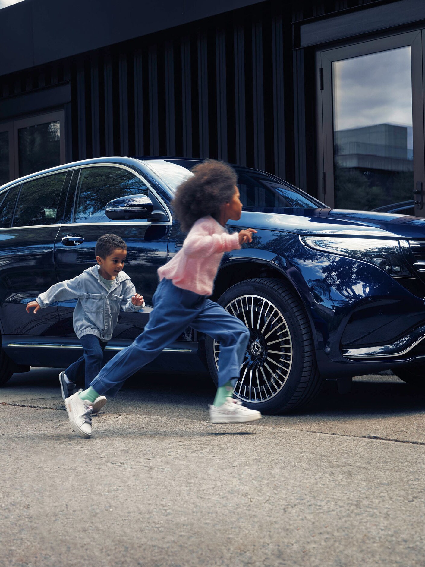 Children walking next to a blue Mercedes-Benz EQC
