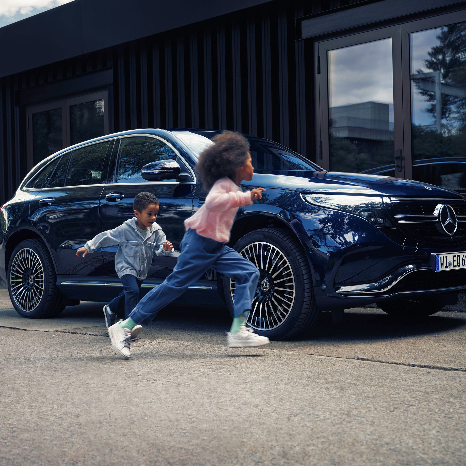 Insurance | Financial Services | Mercedes-Benz Children walking next to a blue Mercedes-Benz EQC