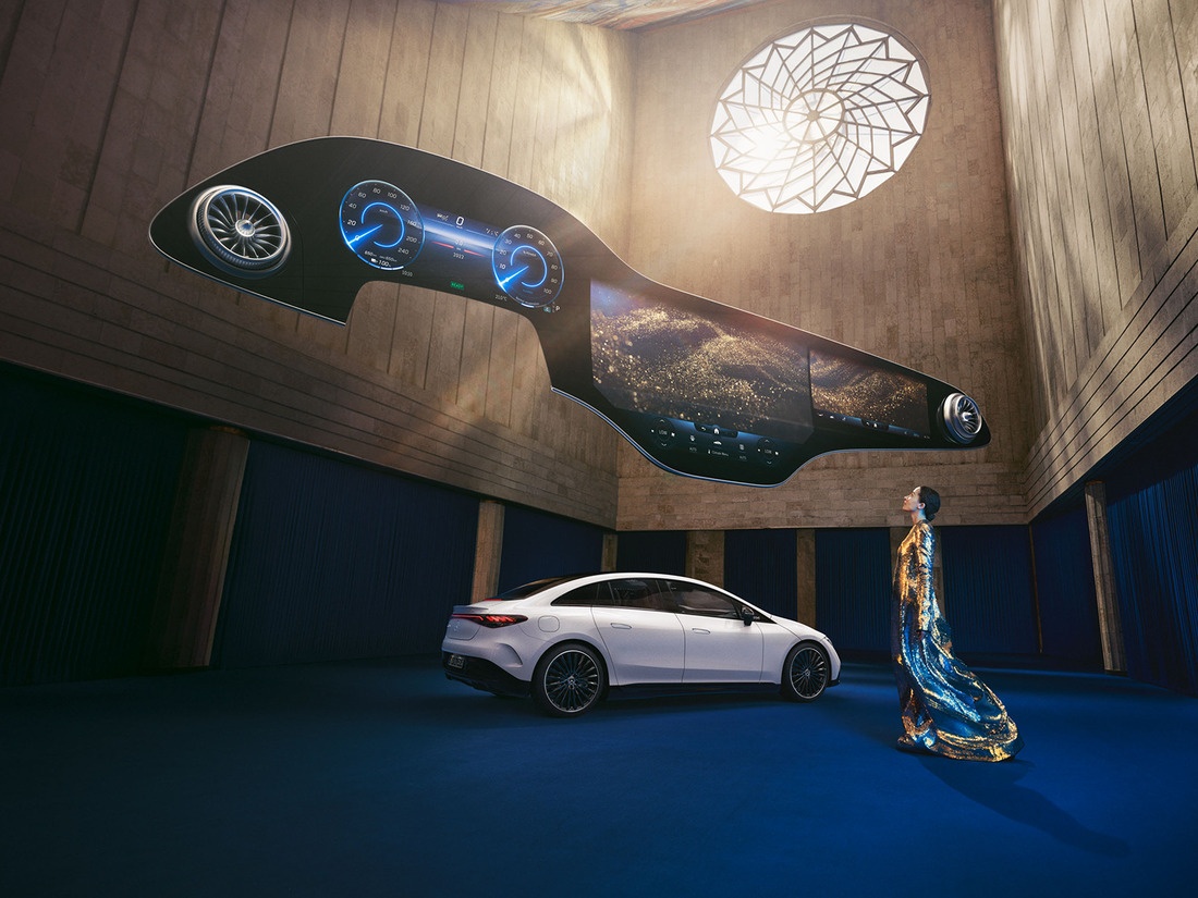 Người phụ nữ đứng trước chiếc xe Mercedes-Benz EQ với màn hình Hyperscreen trôi nổi bên trên. Mercedes-Benz Hyperscreen
