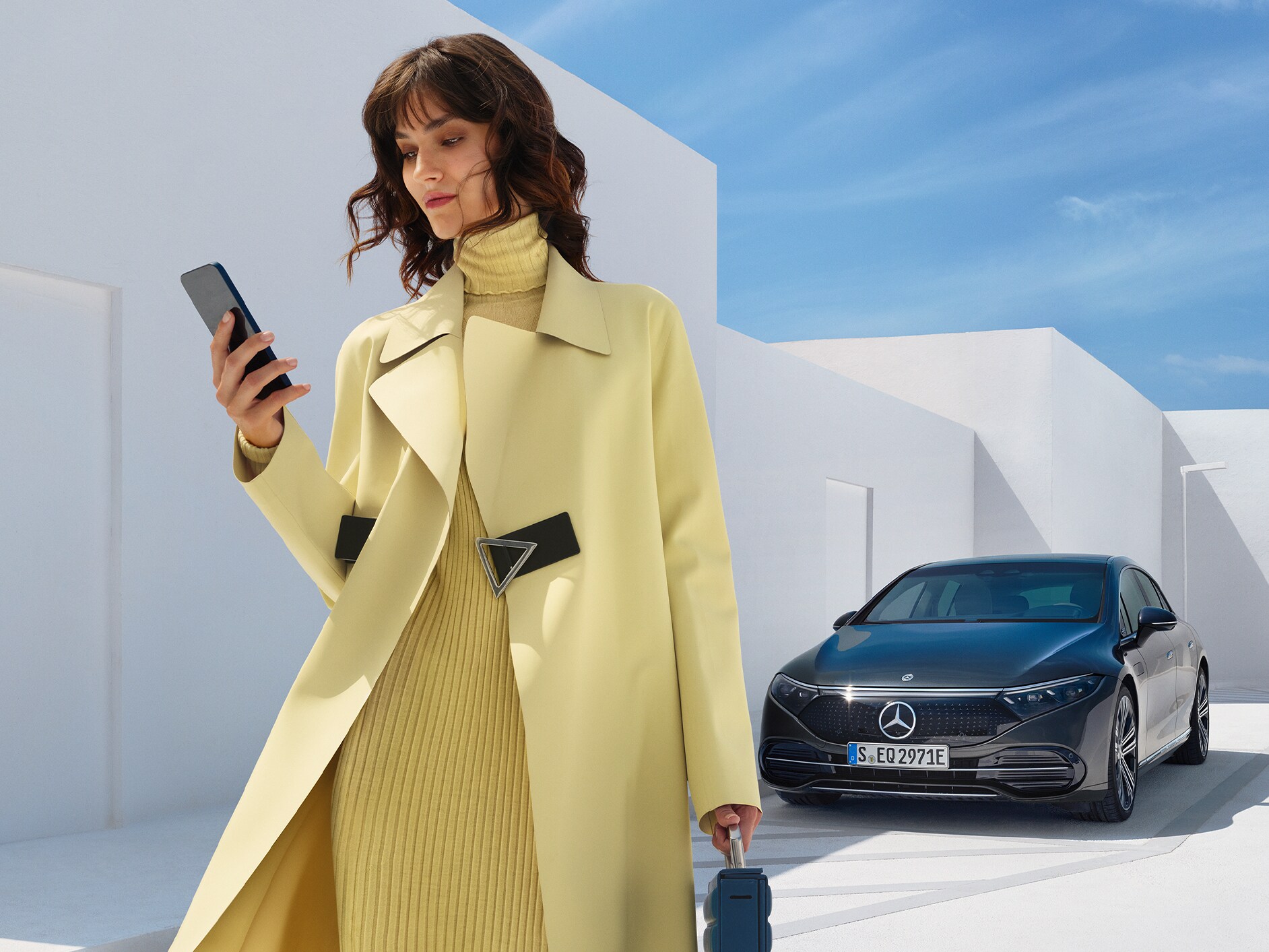 Một người phụ nữ đang đứng trước một chiếc EQS Saloon của Mercedes-Benz.