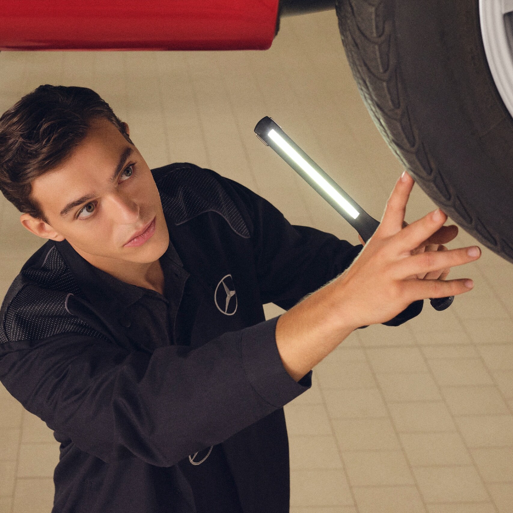 Một kỹ thuật viên của Mercedes-Benz kiểm tra phần dưới một chiếc xe.