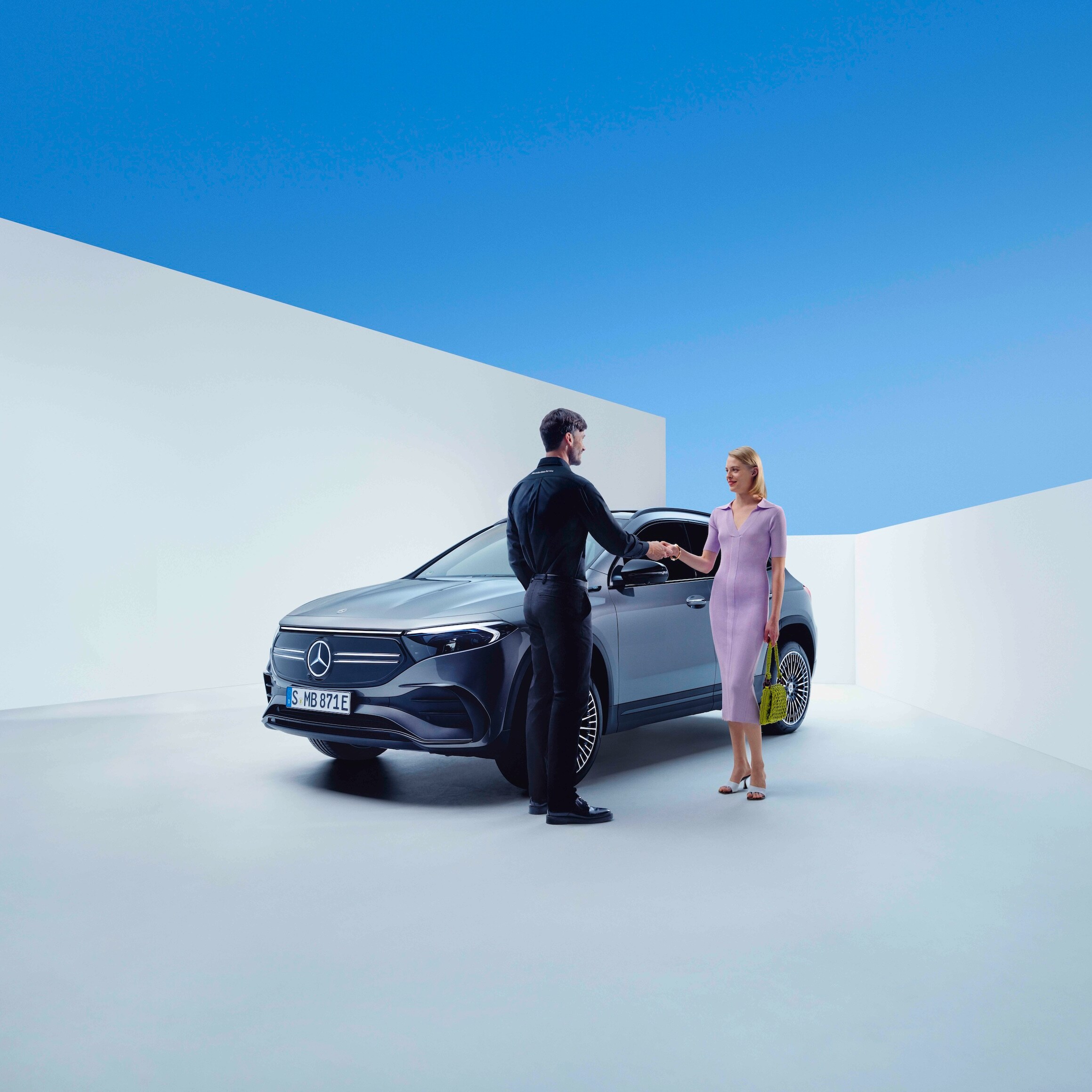 Nhân viên Mercedes-Benz và một người phụ nữ bắt tay nhau trước chiếc xe Mercedes-Benz