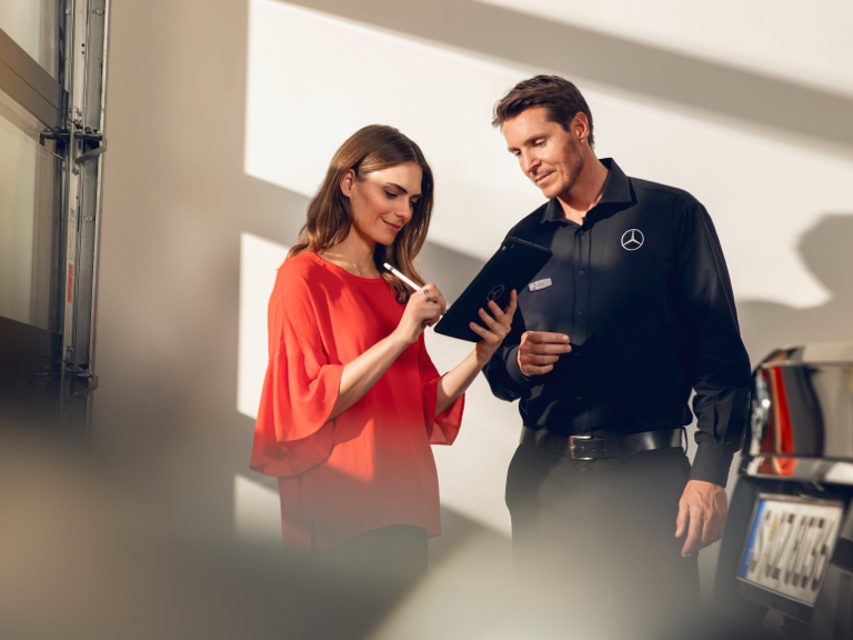 Phụ tùng chính hãng so với Sản phẩm giả mạo Một người phụ nữ kí giấy tờ trên một máy tính bảng trong một xưởng xe.