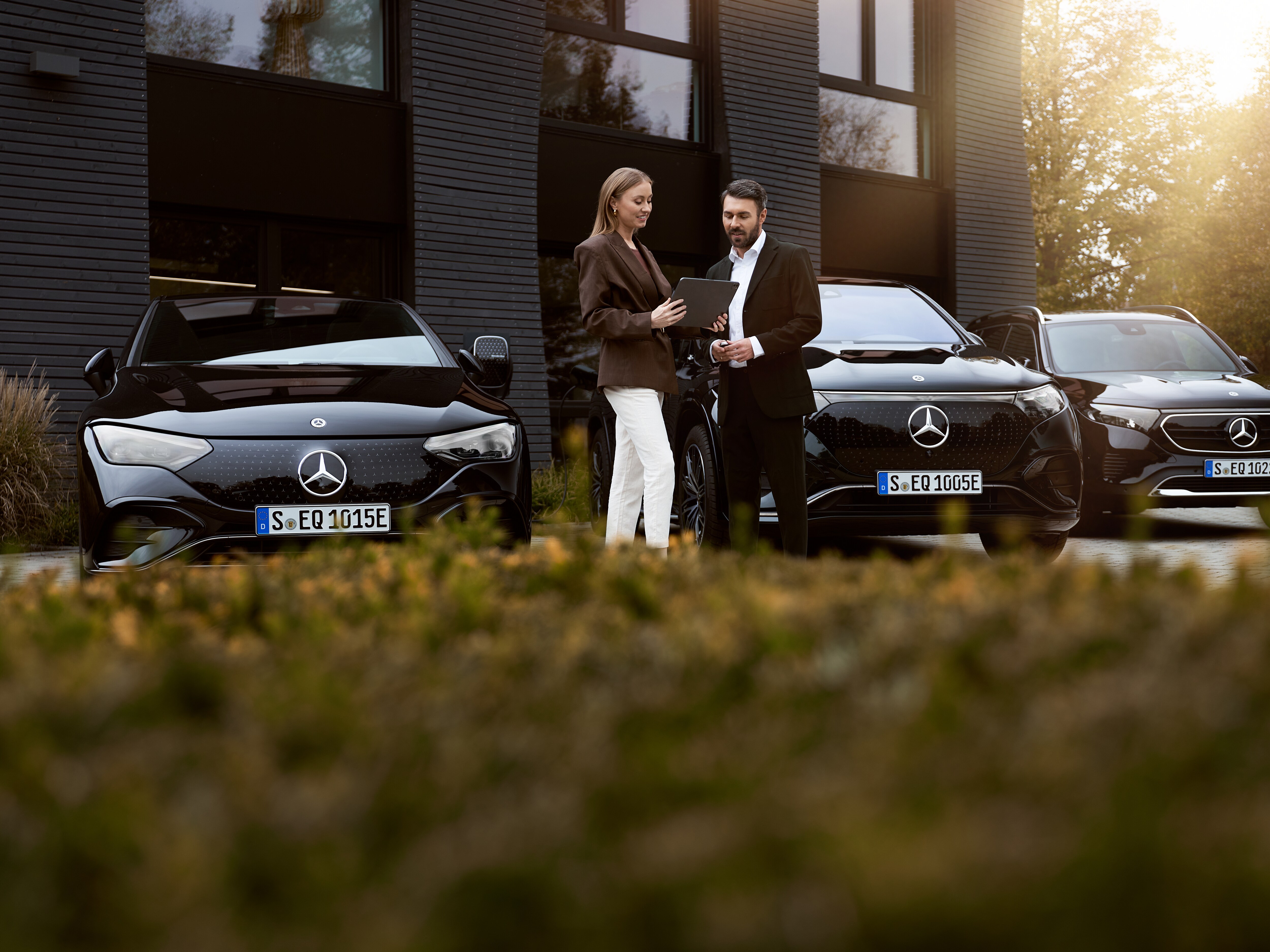 Hình ảnh hai người đang trao đổi giấy tờ và xe điện Mercedes-Benz
