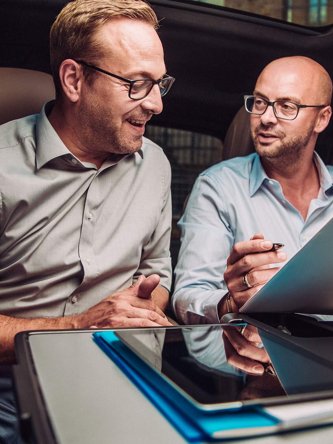 Two men discussing documents inside a Mercedes-Benz vehicle – Exclusive privileges for corporates and key professional groups