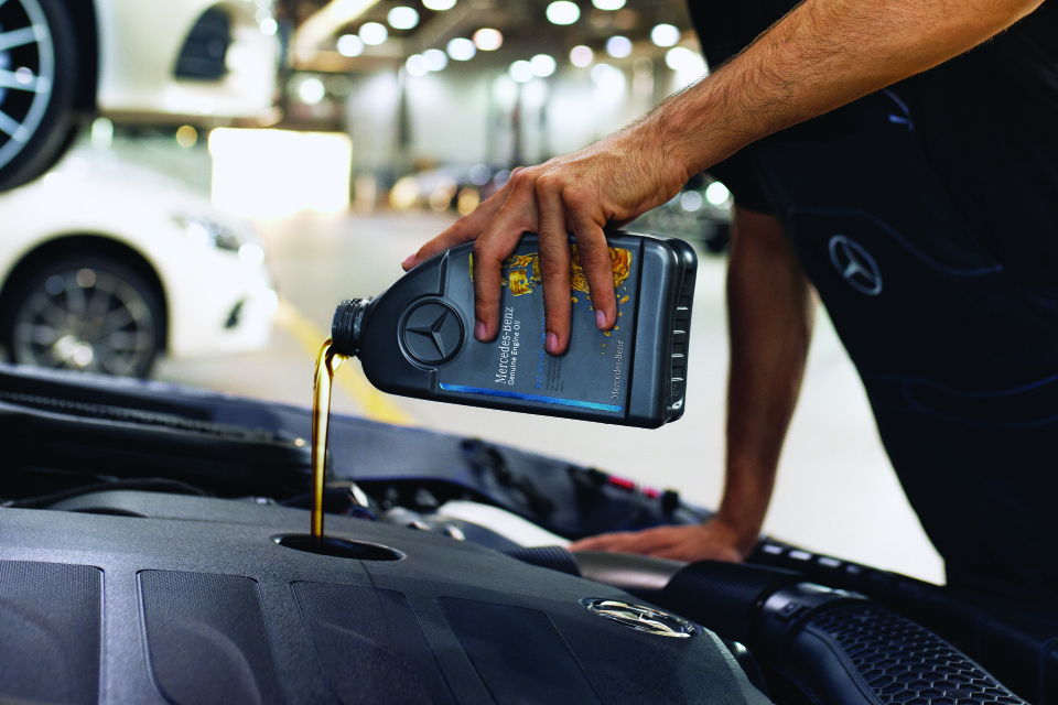 Dầu động cơ chính hãng Mercedes-Benz Cận cảnh khoang động cơ với dầu động cơ chính hãng Mercedes‑Benz đang được rót vào.