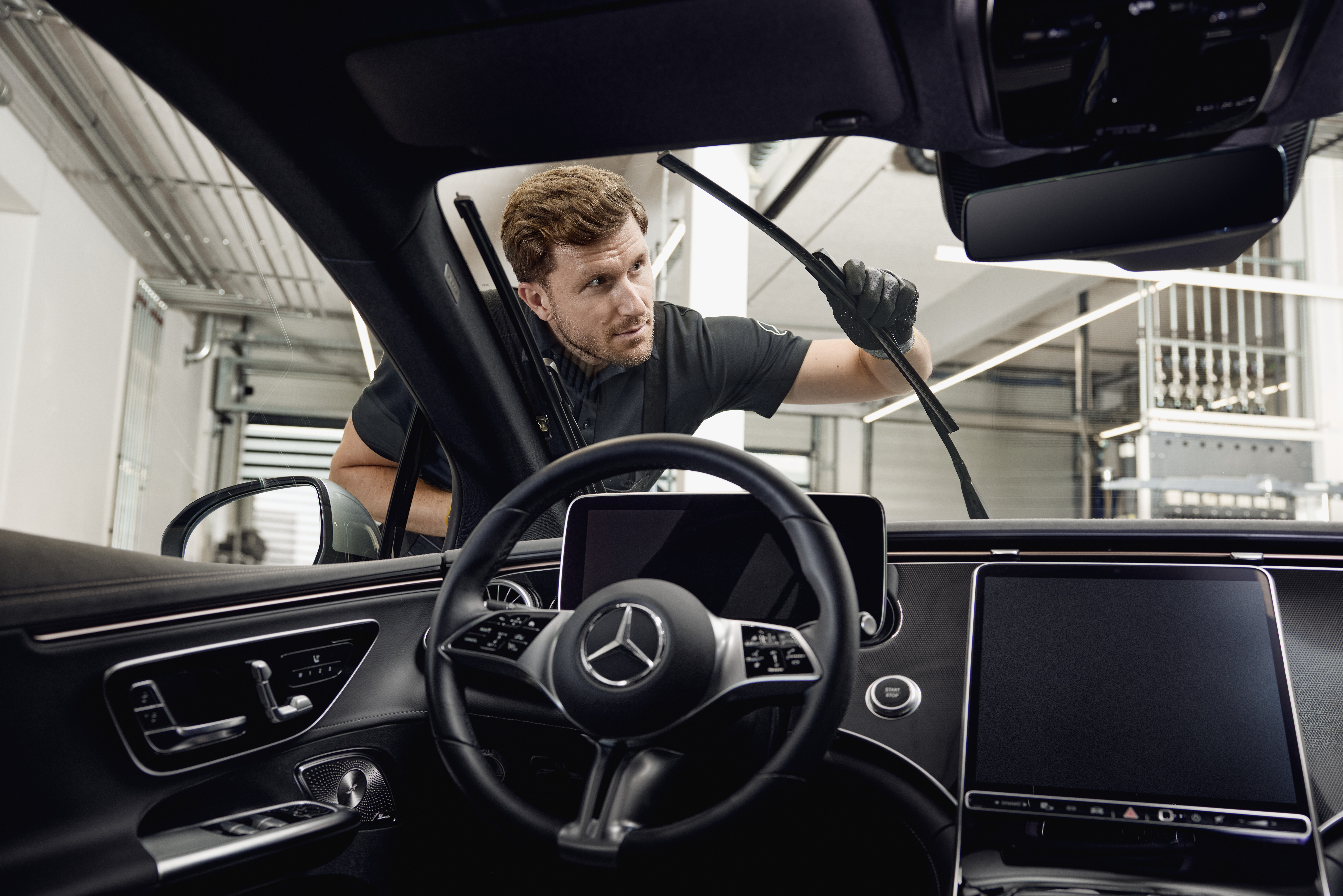 Mercedes-Benz Genuine Wiper Blades Interior view of a Mercedes‑Benz vehicle with a technician exchanging genuine wiper blades.