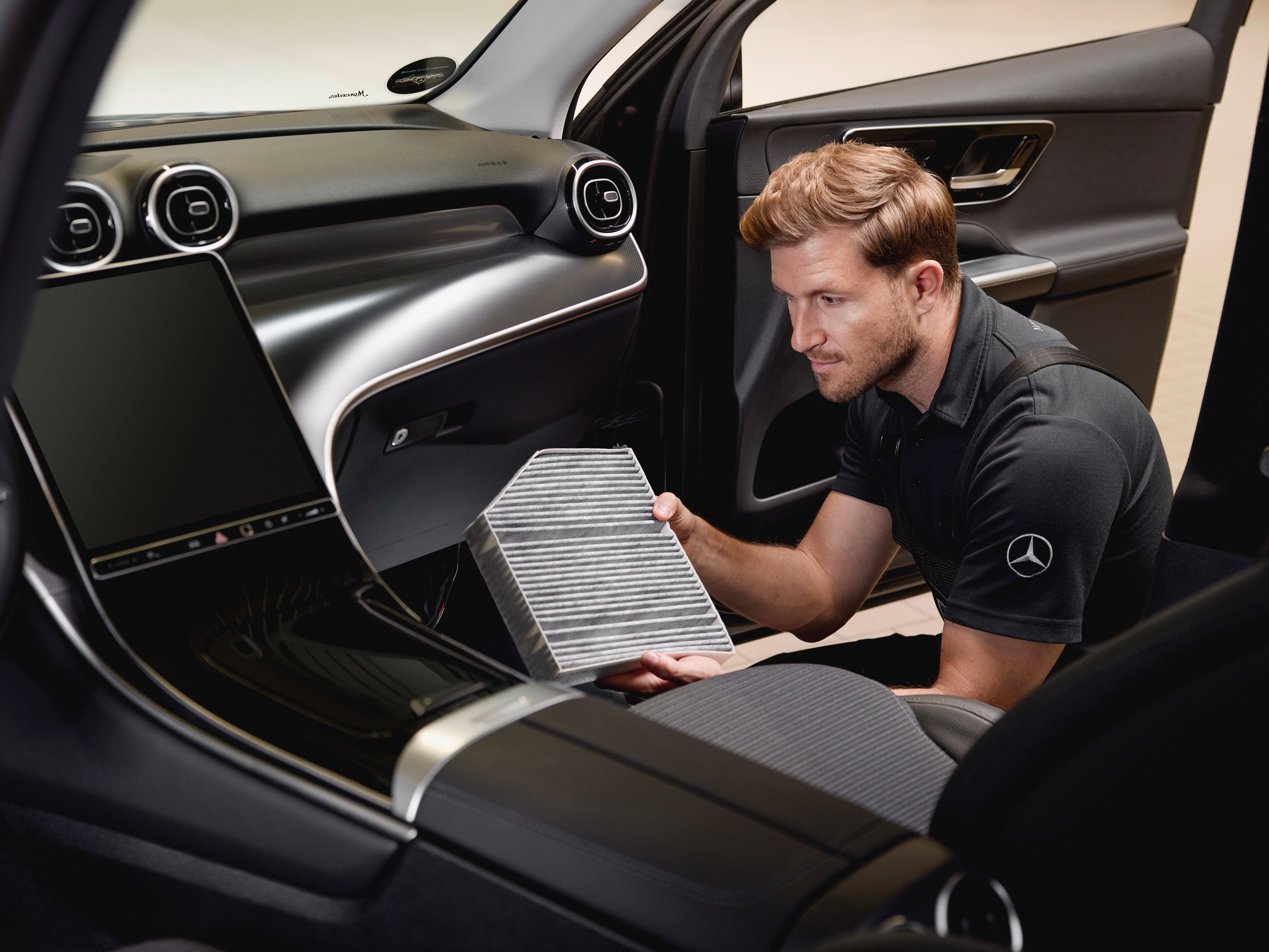 Interior service operation showing the replacement of a cabin air filter using a genuine Mercedes‑Benz part.
