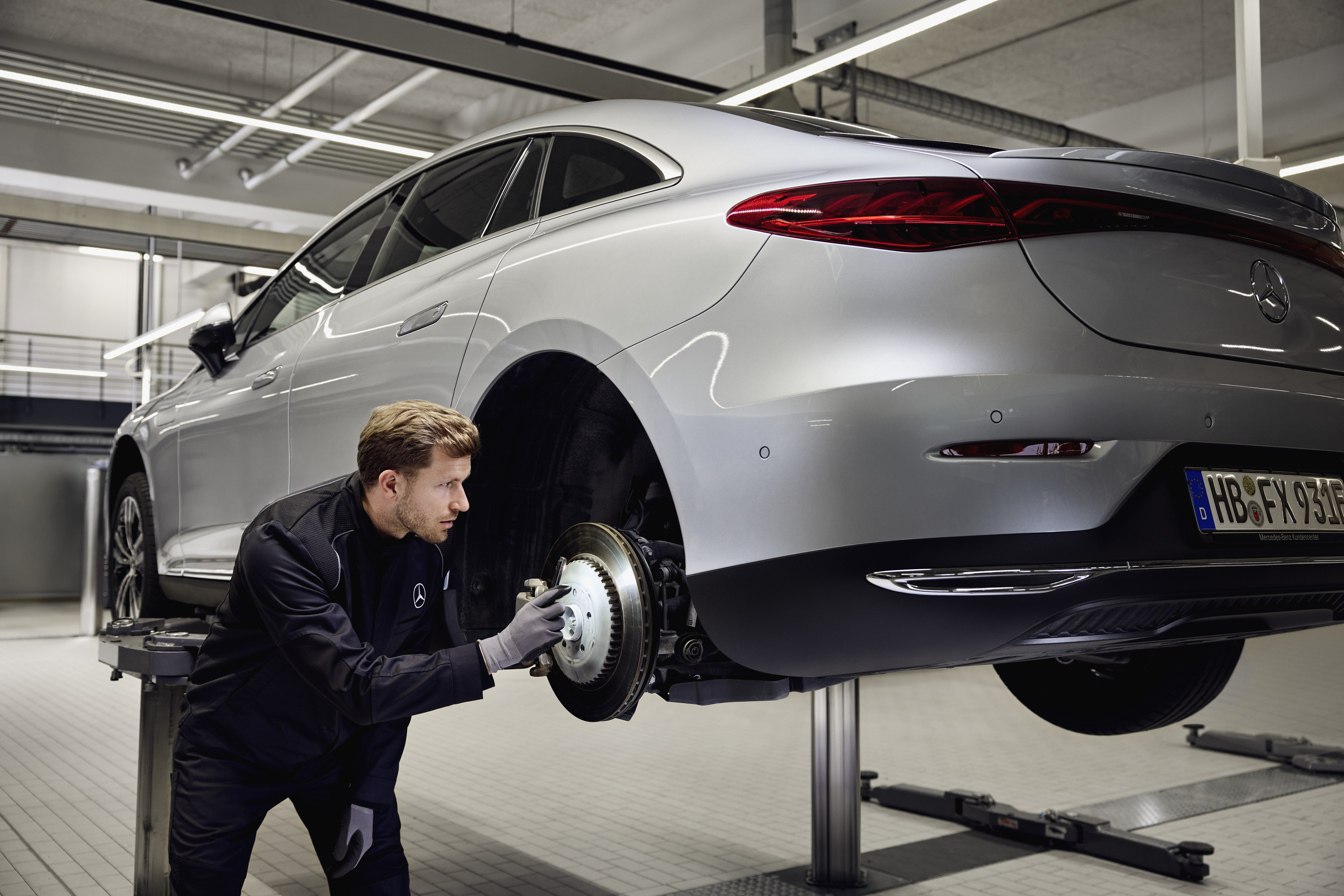 Thay thế phanh chính hãng Mercedes‑Benz Xe Mercedes‑Benz được nâng trên cầu nâng với kỹ thuật viên đang kiểm tra hệ thống phanh sau để thực hiện dịch vụ thay thế phụ tùng chính hãng.
